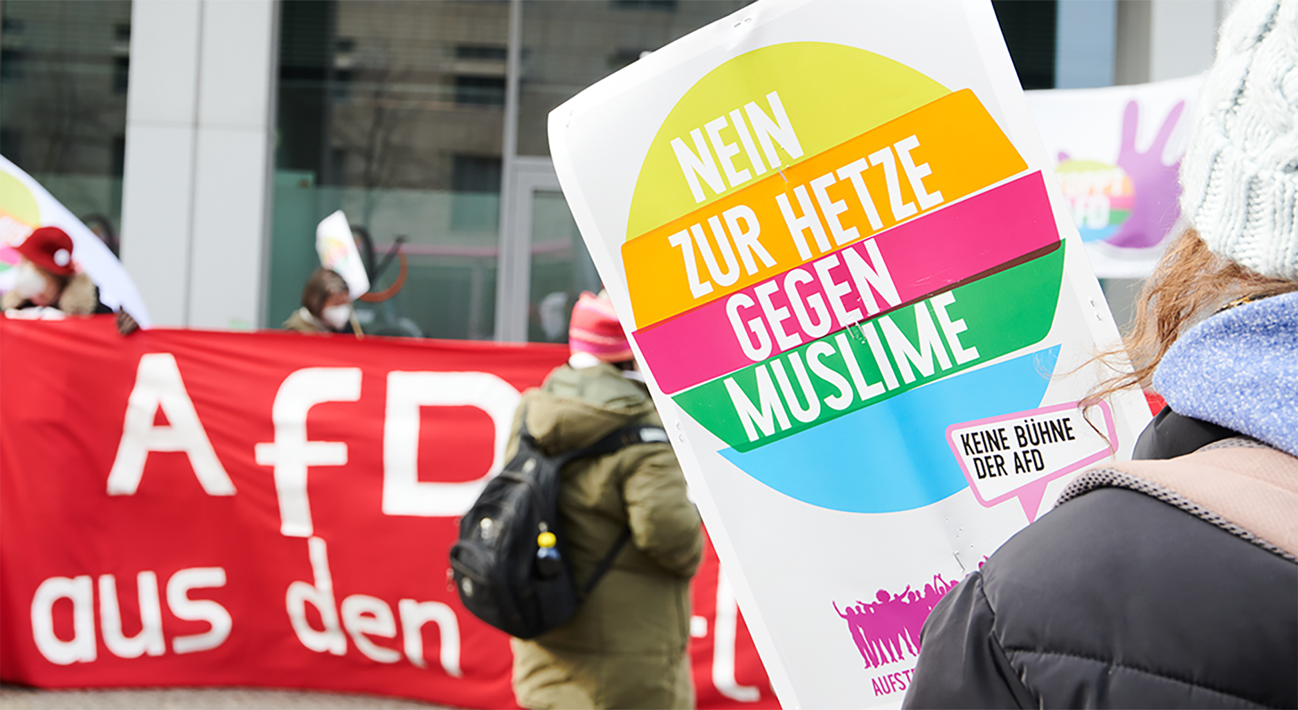 Demonstration mit Banner, auf dem steht "AfD" und Plakat, auf dem steht "Nein zur Hetze gegen Muslime"