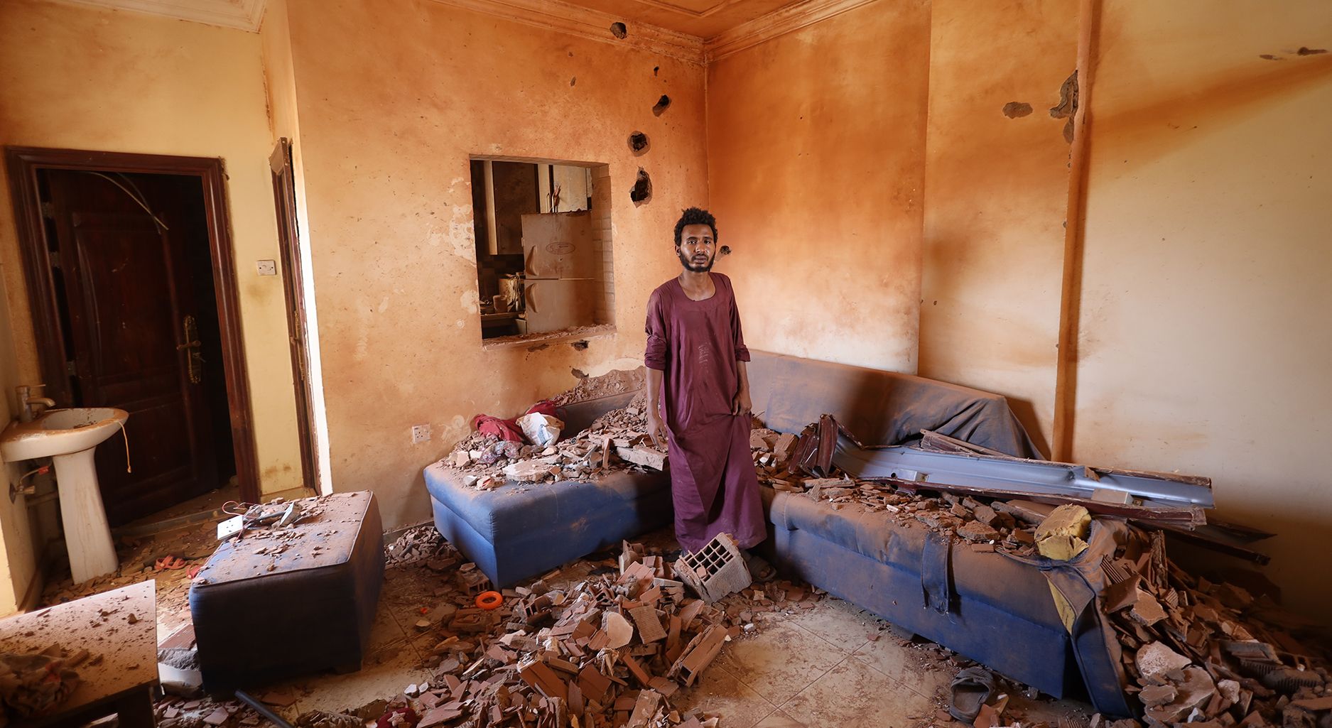 A man stands in a room with a lot of debris.