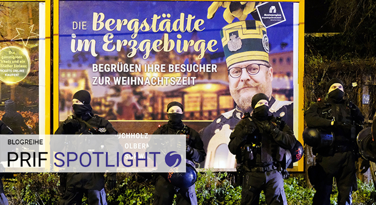 Vor einem großen Plakat über das Erzgebirge stehen Polizisten.