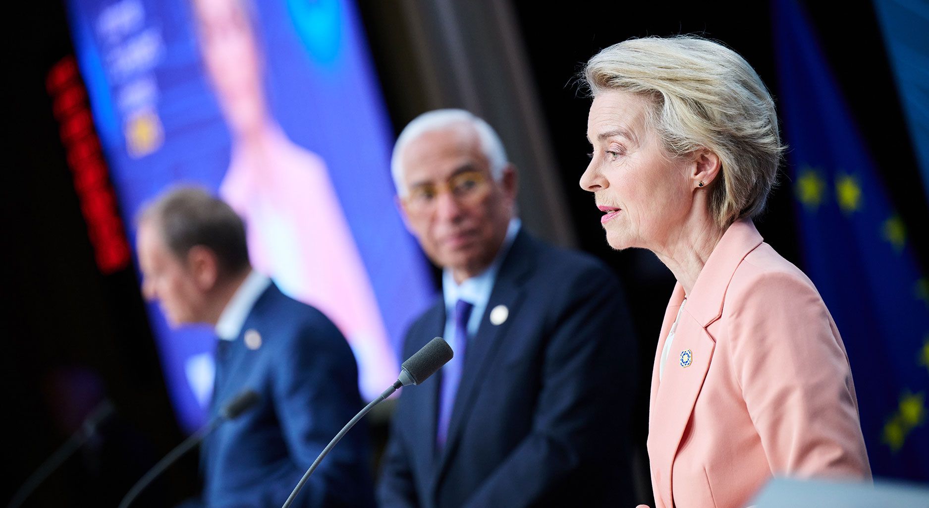 Photo that shows Donald Tusk, Polish Prime Minister, Antonio Costa, President of the European Council, and Ursula von der Leyen on a stage speaking into a microphone.