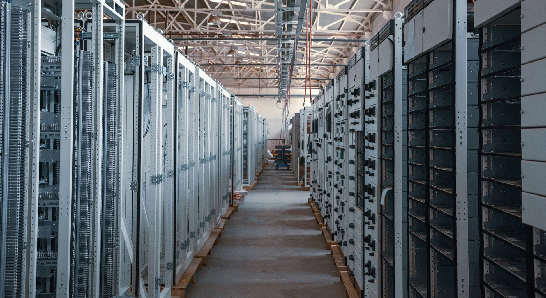 A Serverroom: A long row of servers on the left and right in an industrial hall