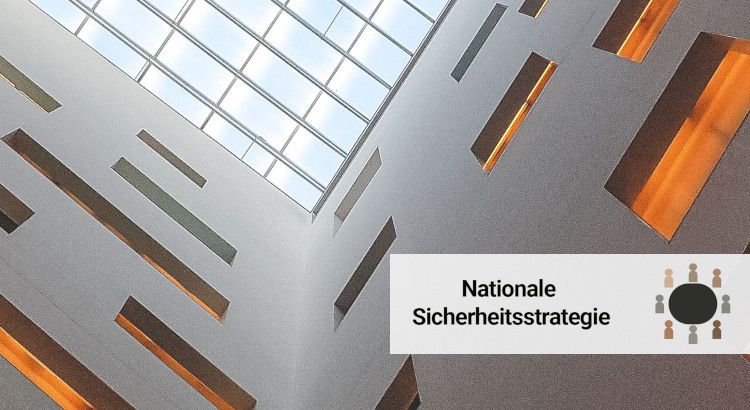 Innere eines grauen Gebäudes, an dem man durch ein gläsernes Dach nach oben guckt.