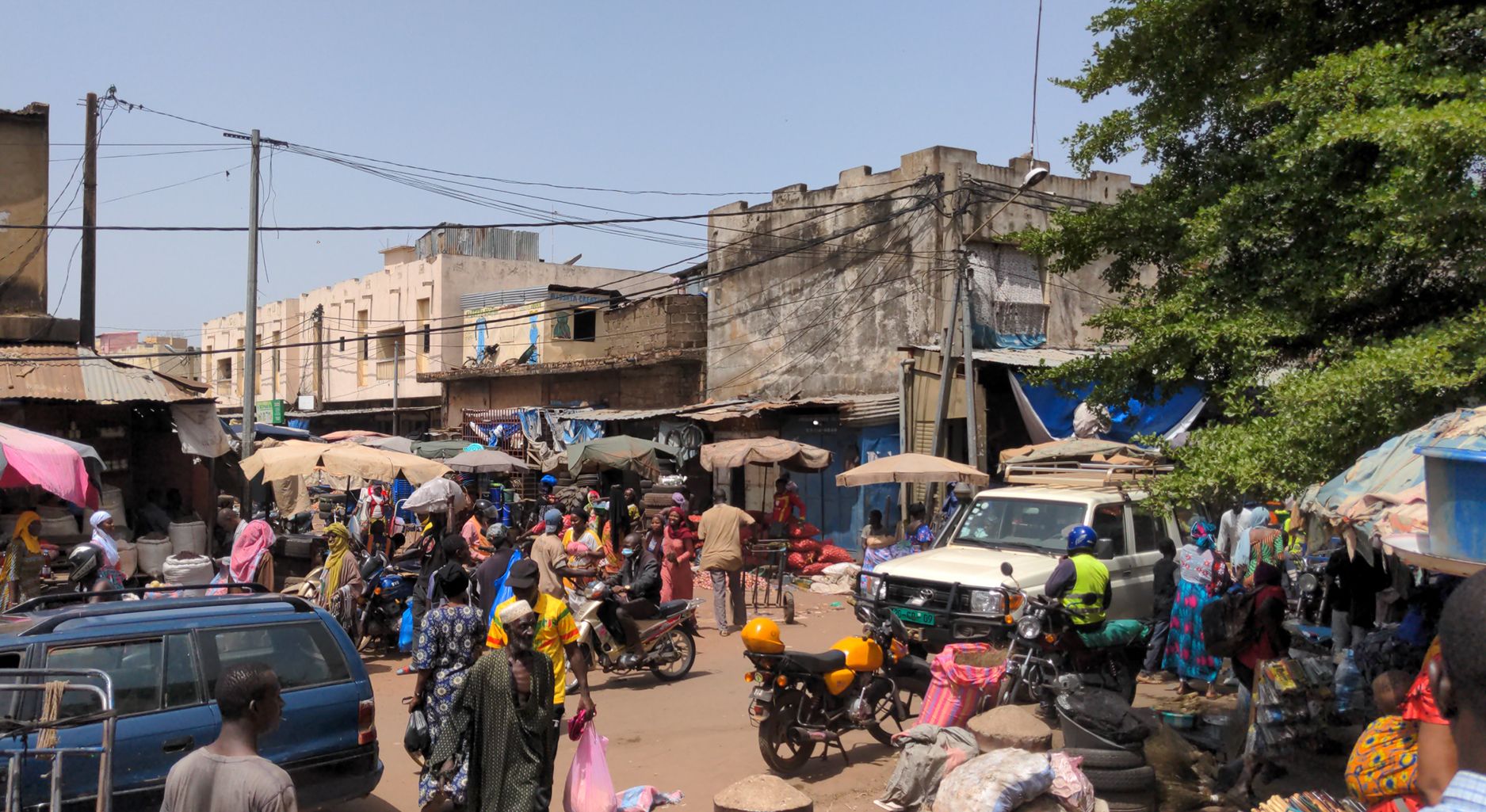 Straßenszene mit Markt, Autos und Menschen in bunter Kleidung