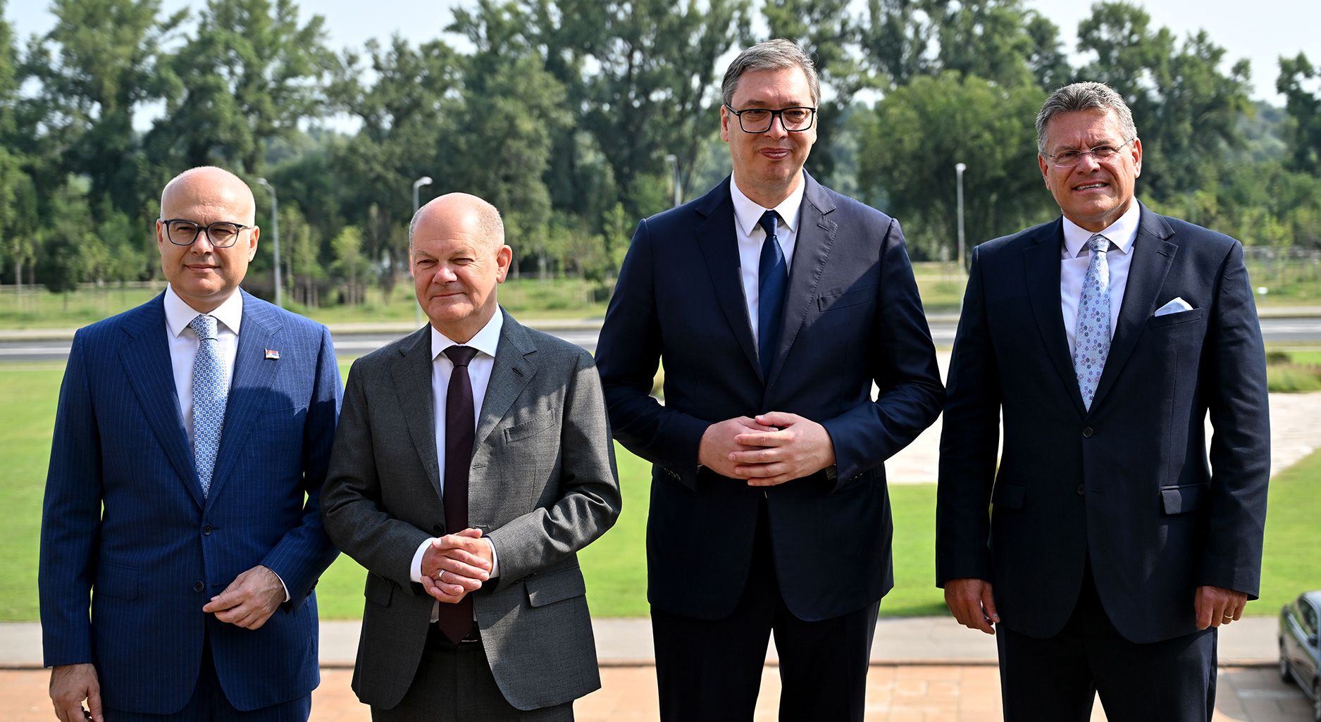 Four men in suits stand next to each other