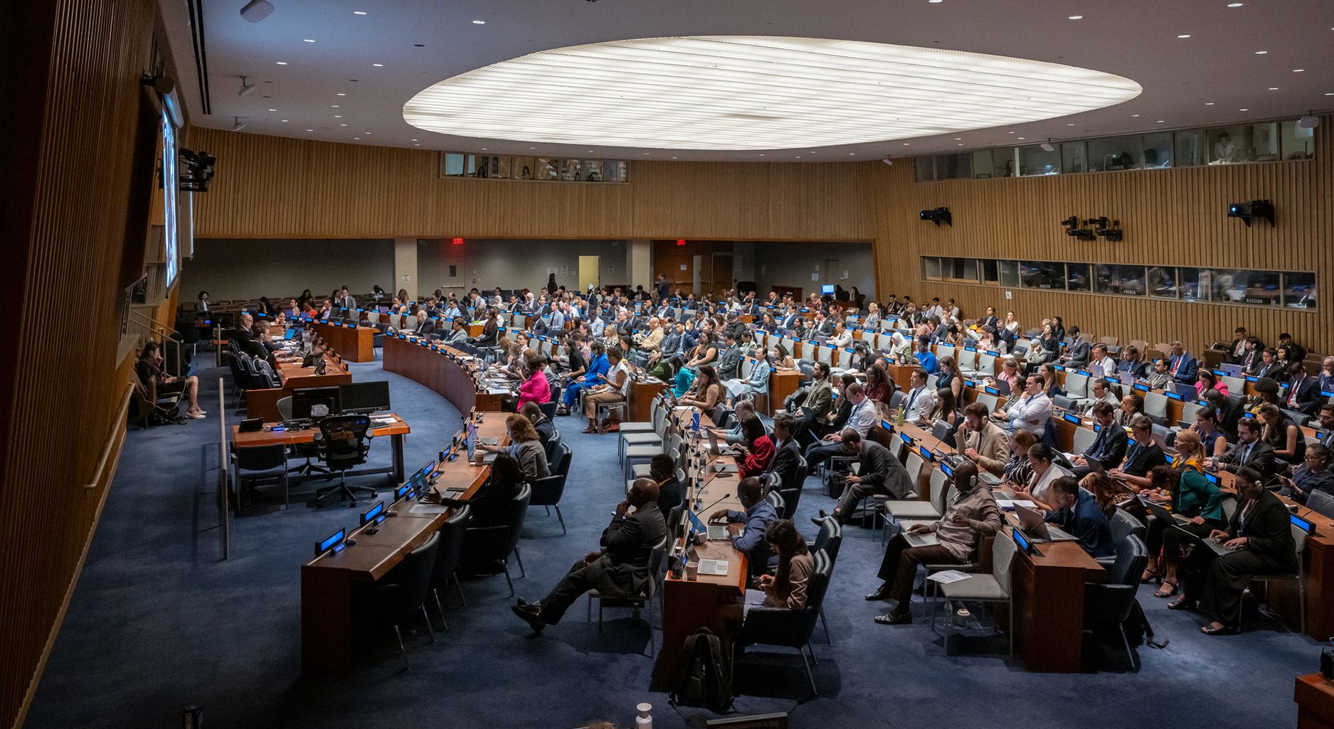 Wide shot of a big conference room filled with people sitting at desks.