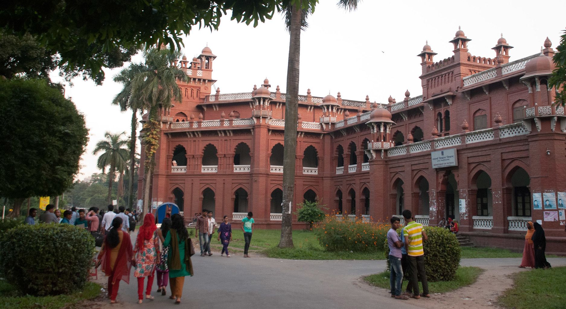 Big red brick building and pedestrian paths with groups of young people walking