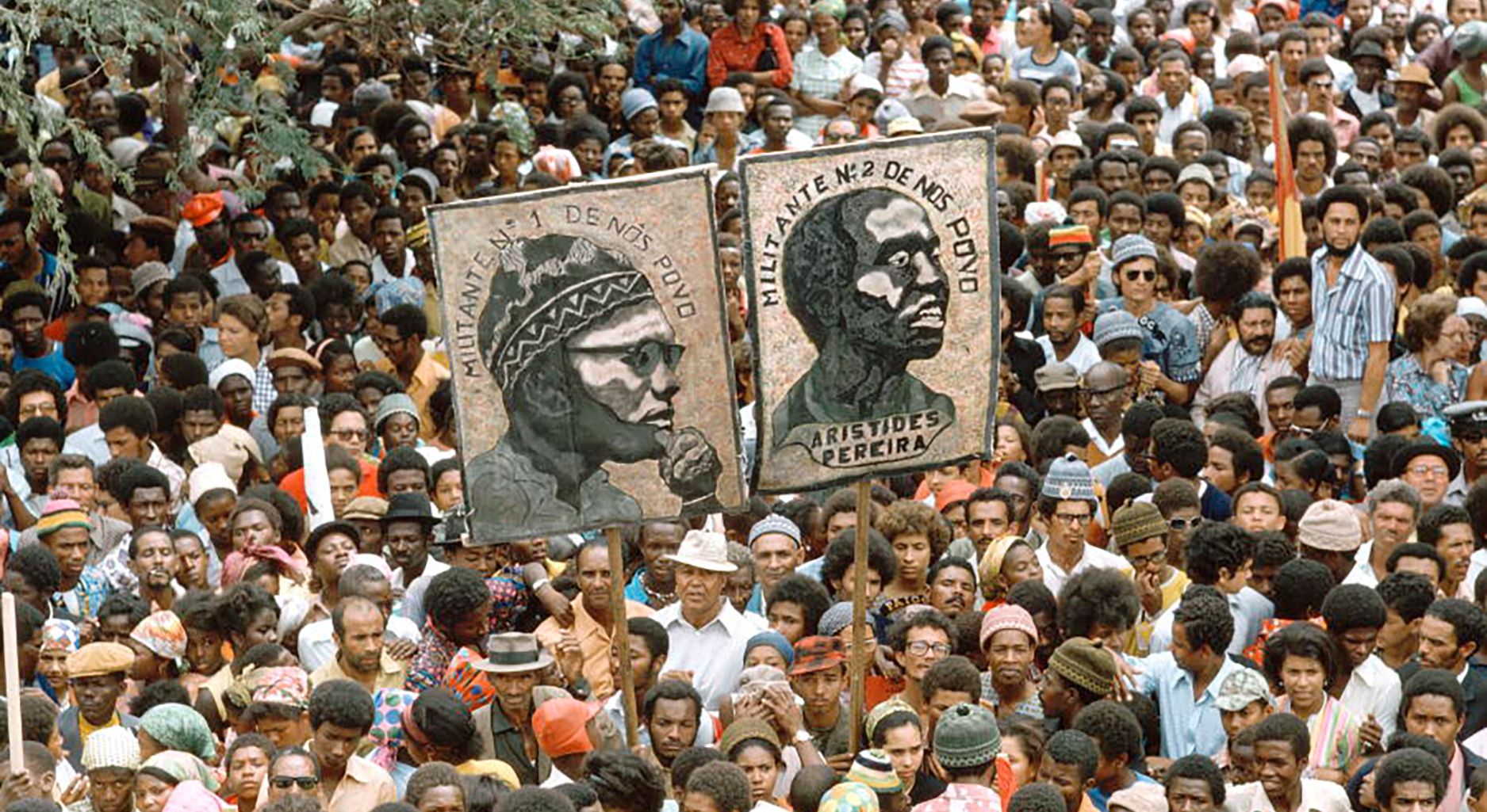 a large crowd holding up two posters showing the head of two men.