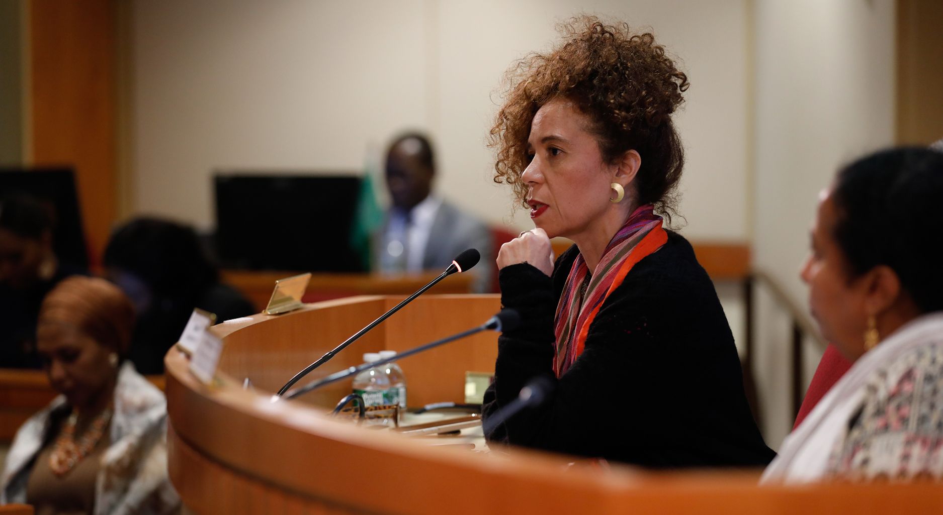 Thania Paffenholz sitting in a large conference room and talking through a microfone