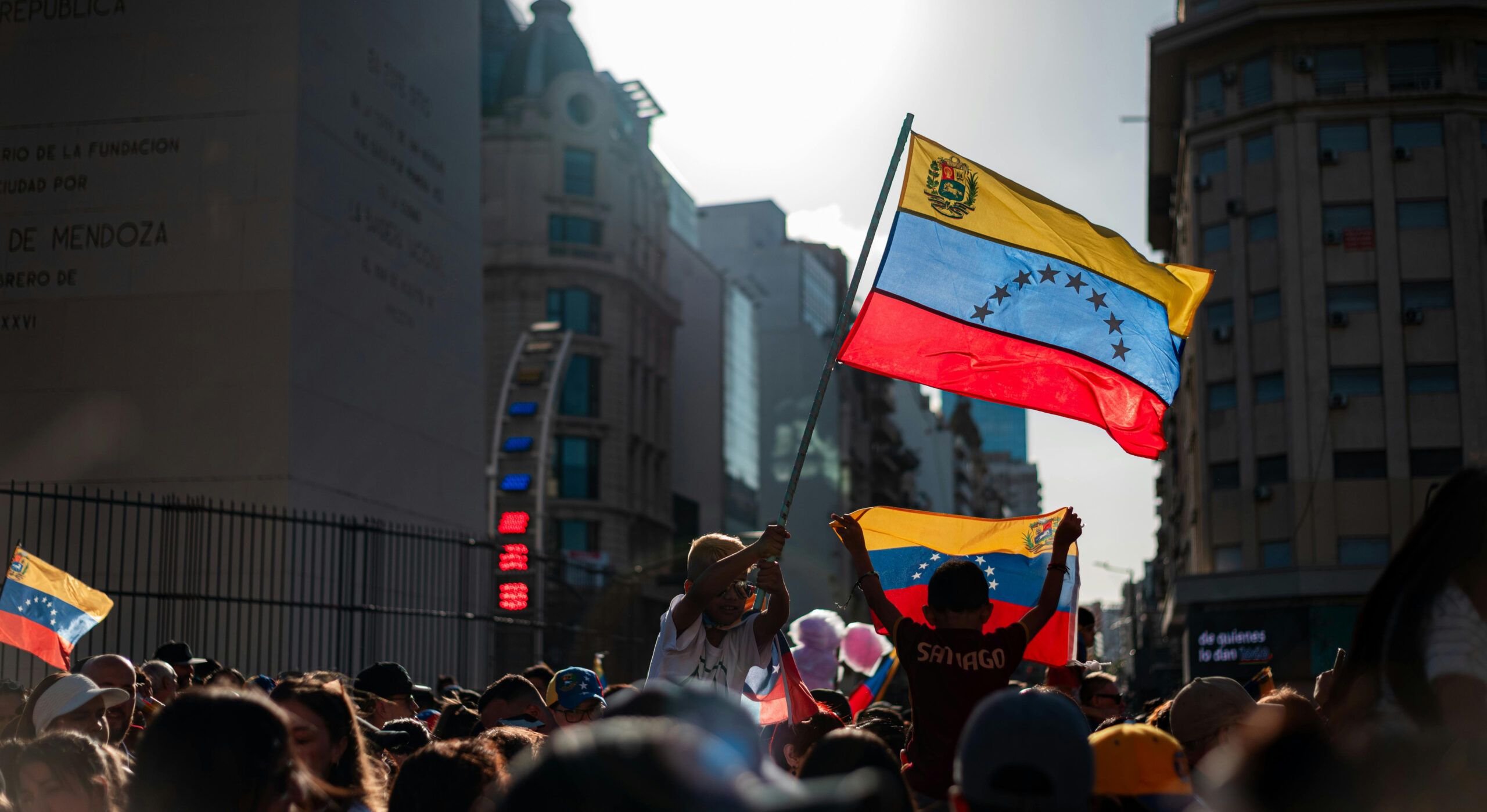 Demonstrators on a street in Buenos Aires. The focus is on two children holding Venezuelan flags in the air.