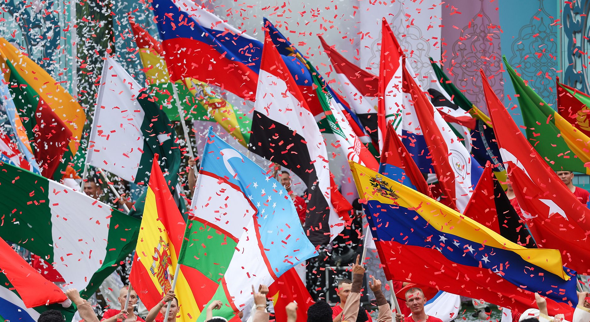 Flags of the BRICS countries are waved in a rain of confetti.
