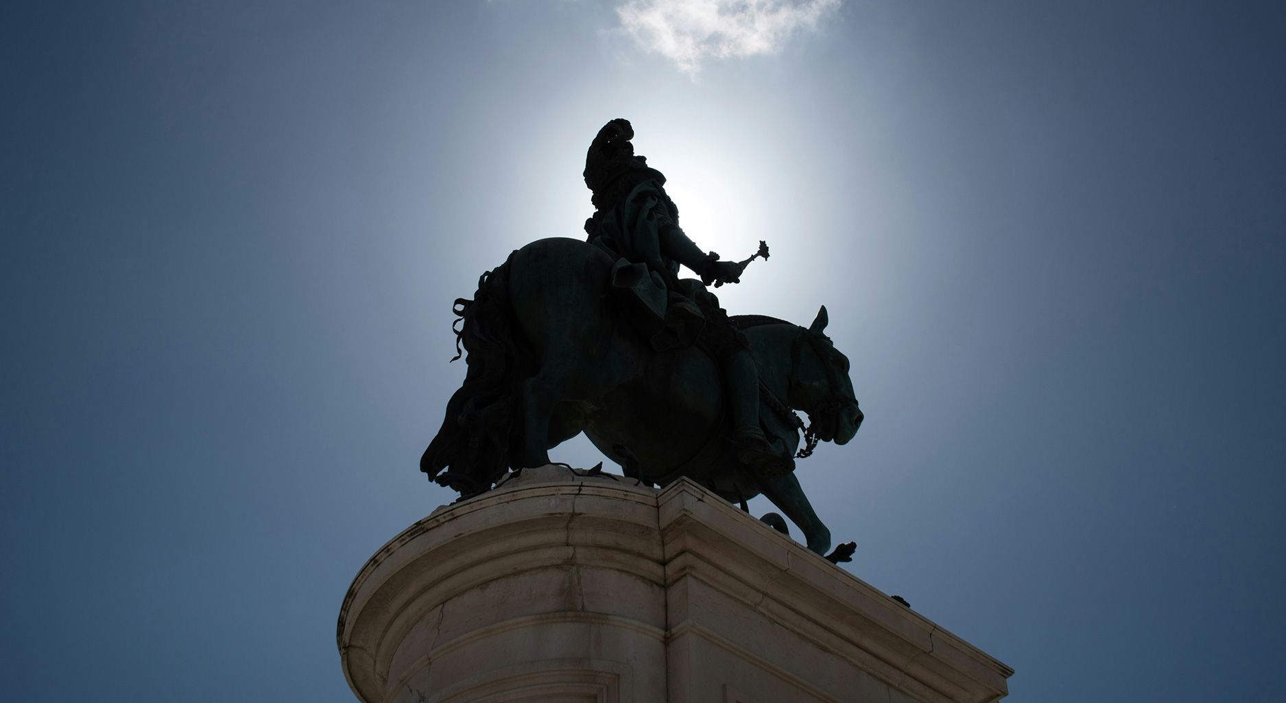 Reiterstandbild, das von hinten unten gegen die Sonne fotografiert wurde, so dass es als Schatten erkennbar ist.