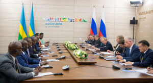 Wladimir Putin und die russische Delegation sitzen an einem Konferenztisch gegenüber von Paul Kagame und der ruandischen Delegation.