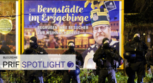 Vor einem großen Plakat über das Erzgebirge stehen Polizisten.