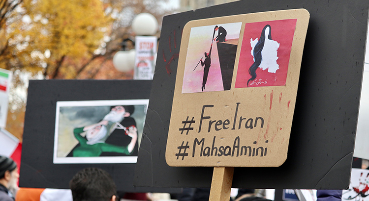 Signs at a protest in solidarity with the protestors in Iran showing the hashtags #FreeIran and #MahsaAmini