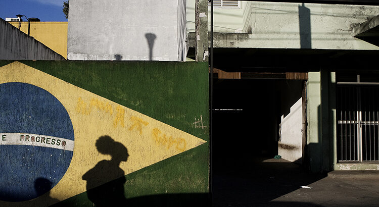 Shadow of a person walking seen on a mural painted with the Brazilian flag