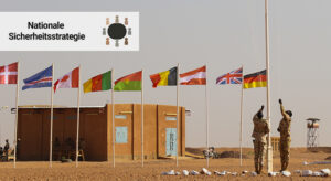 Flaggen verschiedener Länder in einem Camp in Niger und zwei Soldaten, die gerade weitere Flaggen heraufziehen.