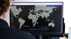 Frau vor Bildschirm mit Website des Uppsala Conflict Data Program, erreichbar unter https://ucdp.uu.se/