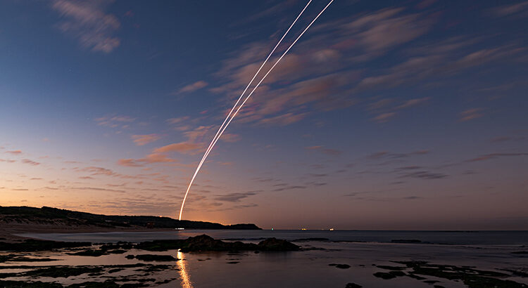 Küste mit Lichtspur von Arrow-3-Rakete am Himmel