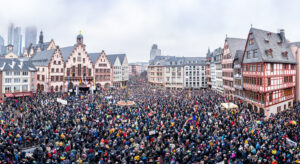 Menschenmenge auf Platz vor Fachwerkhäusern und Wolkenkratzern