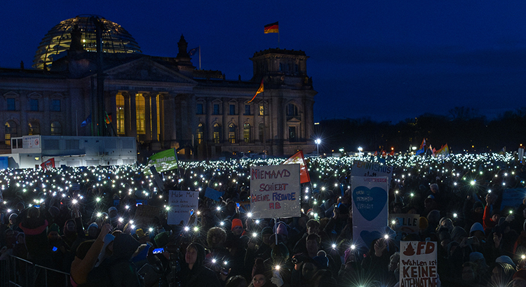 Protestierende Menschen mit Lichtern und Schildern vor dem Reichstag in Berlin