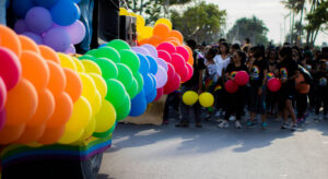 people protesting on a pride parade with colorful balloons.