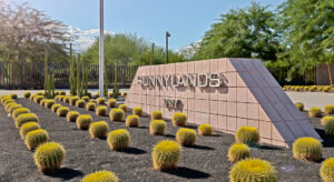 Sunny garden with cacti, surrounded by trees, with a sign that says "Sunnylands 37977"