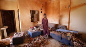 A man stands in a room with a lot of debris.