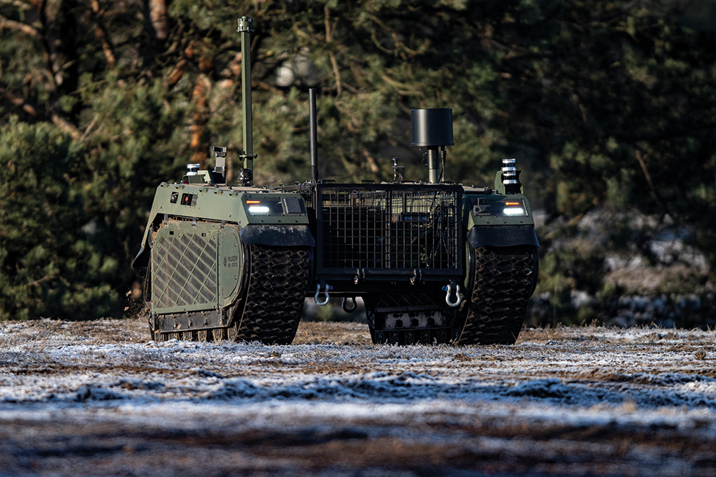 Unmanned military vehicle driving on snowy ground.