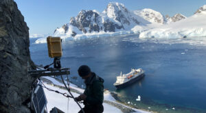 A man climbs on a rock in front of an antarctic scenery