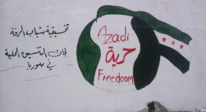Wandgemälde mit syrischer Revolutionsflagge und dem Wort "Freiheit" auf Arabisch, Englisch und Kurdisch, daneben arabische Schriftzeichen.