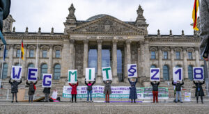 Protestierende vor dem Reichstagsgebäude in Berlin halten Schilder hoch, aus denen sich zusammengesetzt der Text ergibt "Weg mit §218"