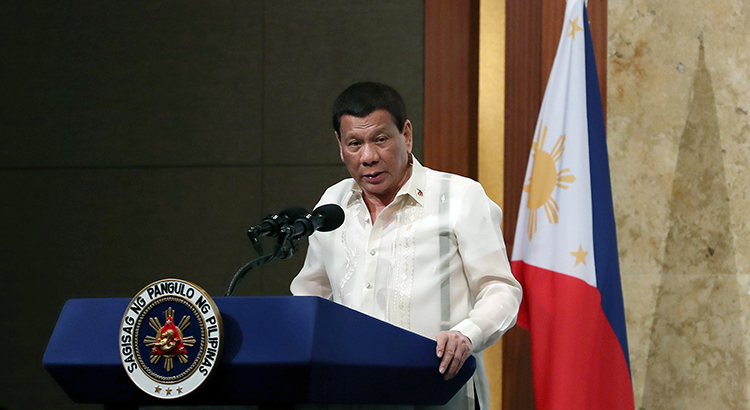 Former President Rodrigo Duterto stands at a podium in front of the flag of the Philippines.