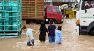 A group of Filipinos walking through knee-high water on a street.