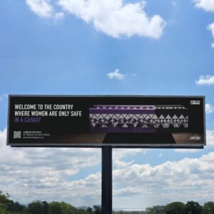 Bilboard on the highway from the women's rights organization ‘Women For Change’. It shows a purple and white patterned coffin with the inscription: ‘Welcome to the country where women are only safe in a casket’.