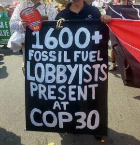 Demonstrant mit Schild '16.000+ Fossil Fuel Lobbyists present at COP30'.