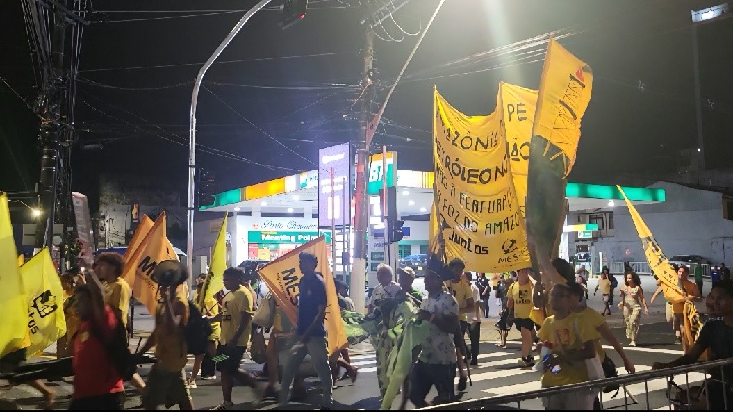 Straßenprotest von Aktivist*innen: Menschen halten gelbe Protestschilder in die Höhe.