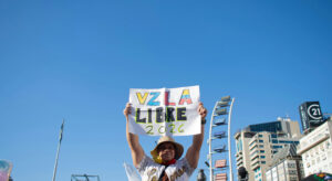 Demonstrant hält Protestschild in die Luft. Aufschrift: 'VZLA libr 2026'