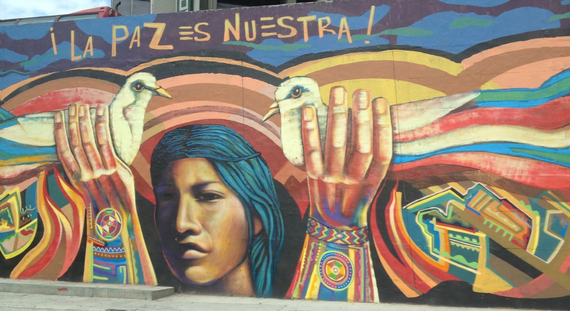 Colorful graffiti depicting a woman holding two doves aloft. Above it reads “La paz es nuestra.”